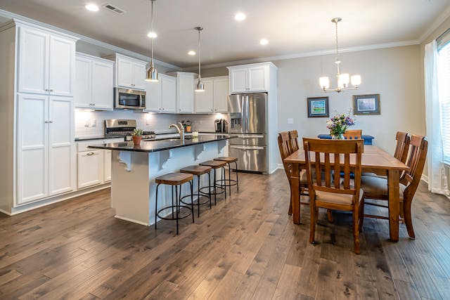 a white kitchen with dark wood flooring and a large table